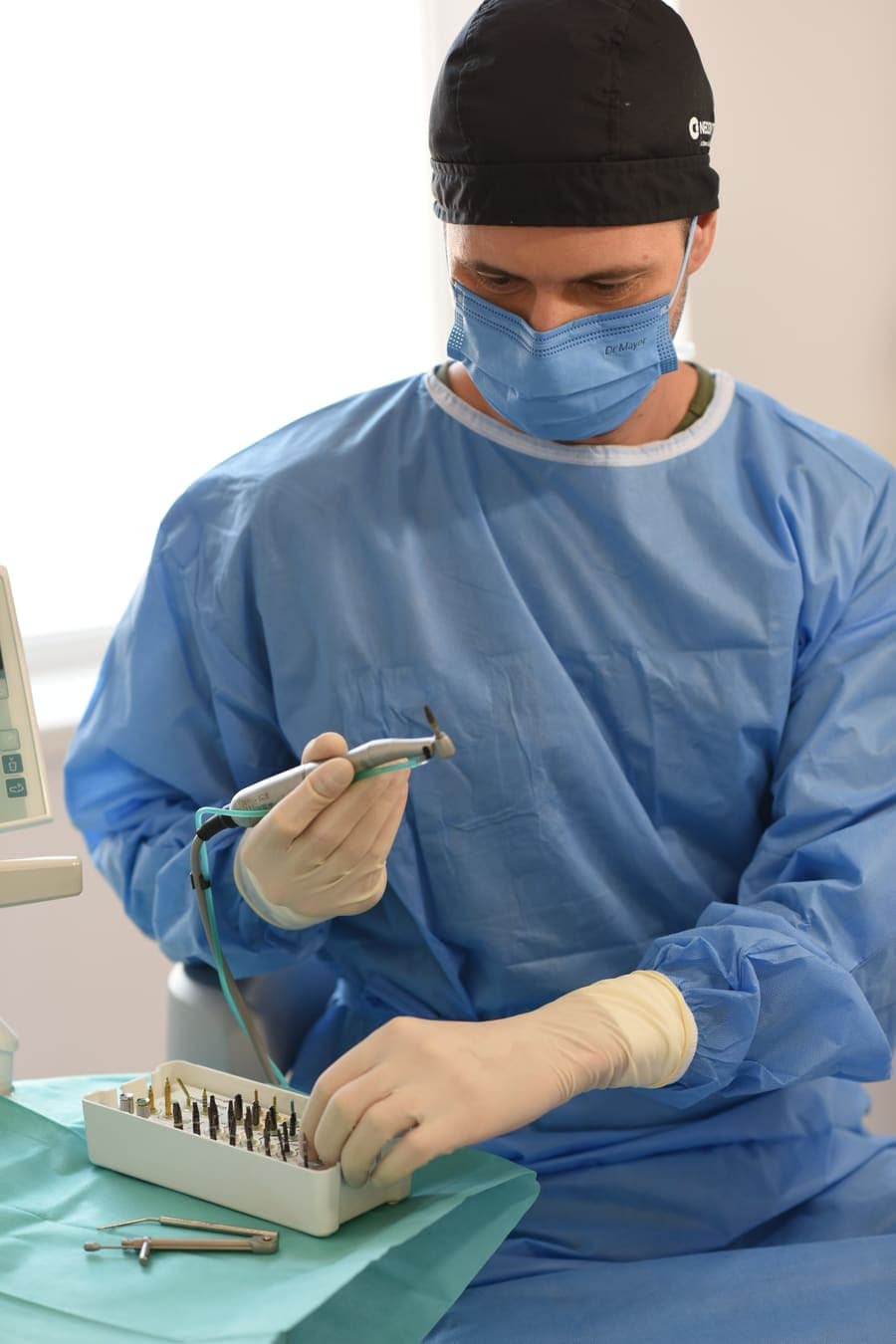 Dr. Paul Man, în echipament chirurgical steril, pregătind piesa de mână deasupra trusei de implantologie