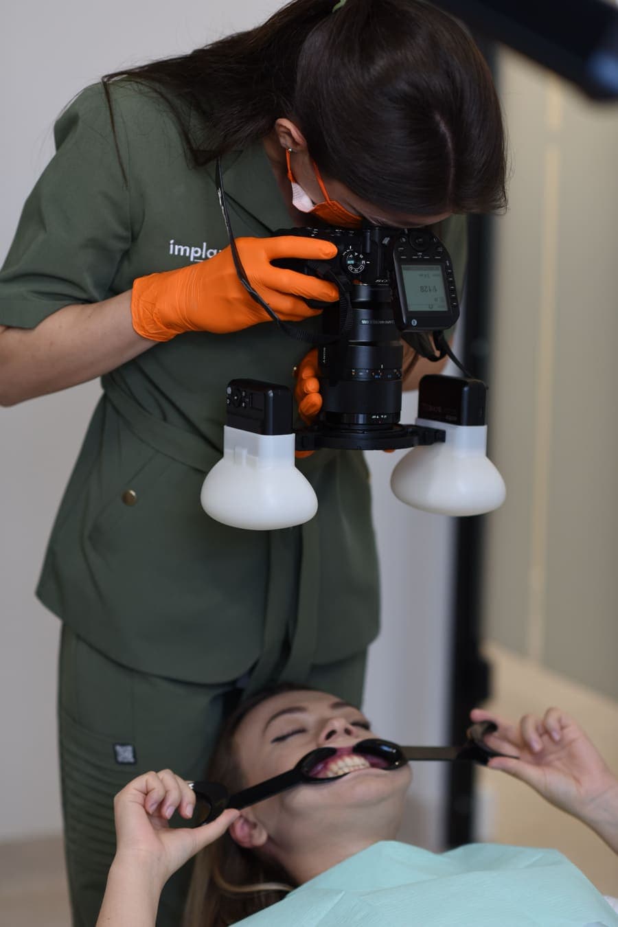 Medic fotografiind arcadele unei paciente cu aparat foto profesional și depărtătoare, pentru documentarea cazului
