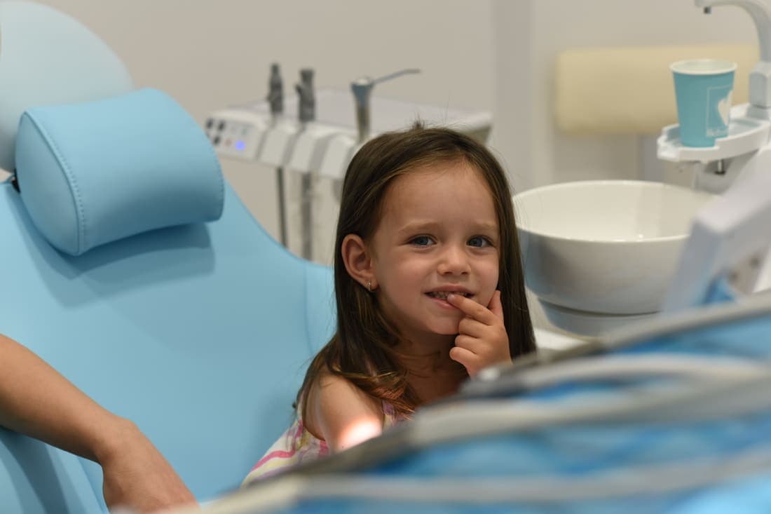 Fetiță zâmbind în unitul dentar, în cabinetul de pedodonție al clinicii