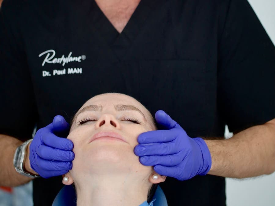 Dr. Paul Man evaluând conturul facial al unei paciente înainte de tratamentul cu Sculptra