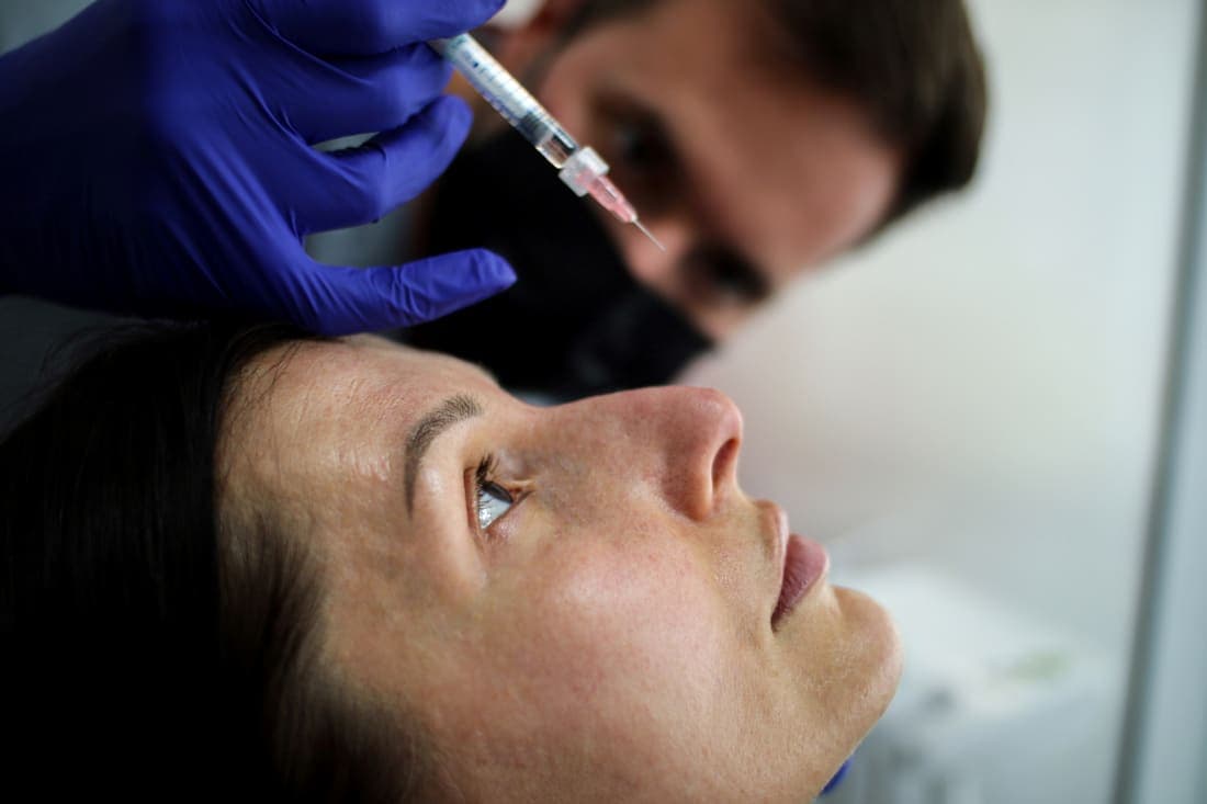 Injectare de acid hialuronic în zona periorbitală, cu ac fin, la o pacientă întinsă pe unit