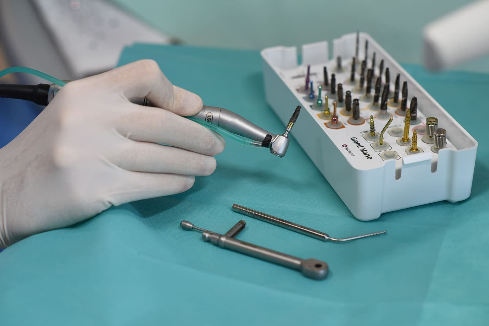Medic pregătind trusa chirurgicală și implantul dentar din titan înainte de inserare
